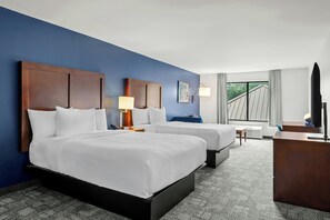 A hotel room with two beds, a desk, a chair, a TV, and a window with curtains. - City Express by Marriott Milford Cooperstown (Milford)