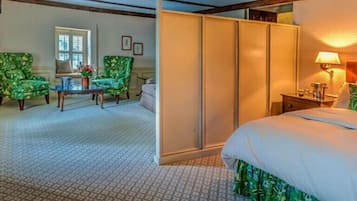 A hotel room with a bed, a desk, two chairs, a wardrobe, and a window.
