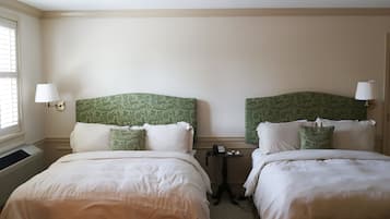 Quarto de hotel com duas camas, cada uma com cabeceira verde, roupa de cama branca e abajures.