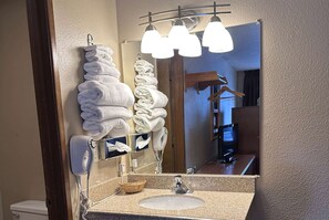 A bathroom with a sink, mirror, towel rack, and a hairdryer.