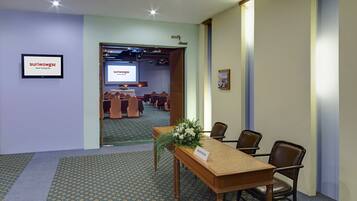 Una sala de conferencias con una mesa de madera, sillas, un arreglo floral y un cartel que indica 'registro'.