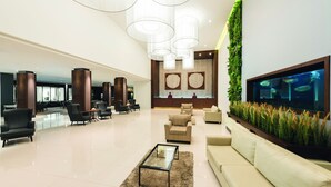 Un hall d’entrée spacieux au design moderne, agrémenté d’un grand aquarium, de sièges confortables et d’un mur décoratif orné de plantes.