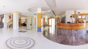 A hotel lobby with a reception desk, seating area, and a patterned floor. - Invisa Hotel Ereso All Inclusive (Santa Eulalia del Rio)