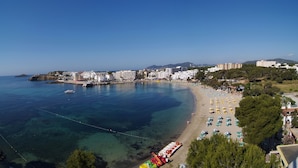 A coastal town with a beach, clear blue waters, and buildings along the shore. - Invisa Hotel Ereso All Inclusive (Santa Eulalia del Rio)