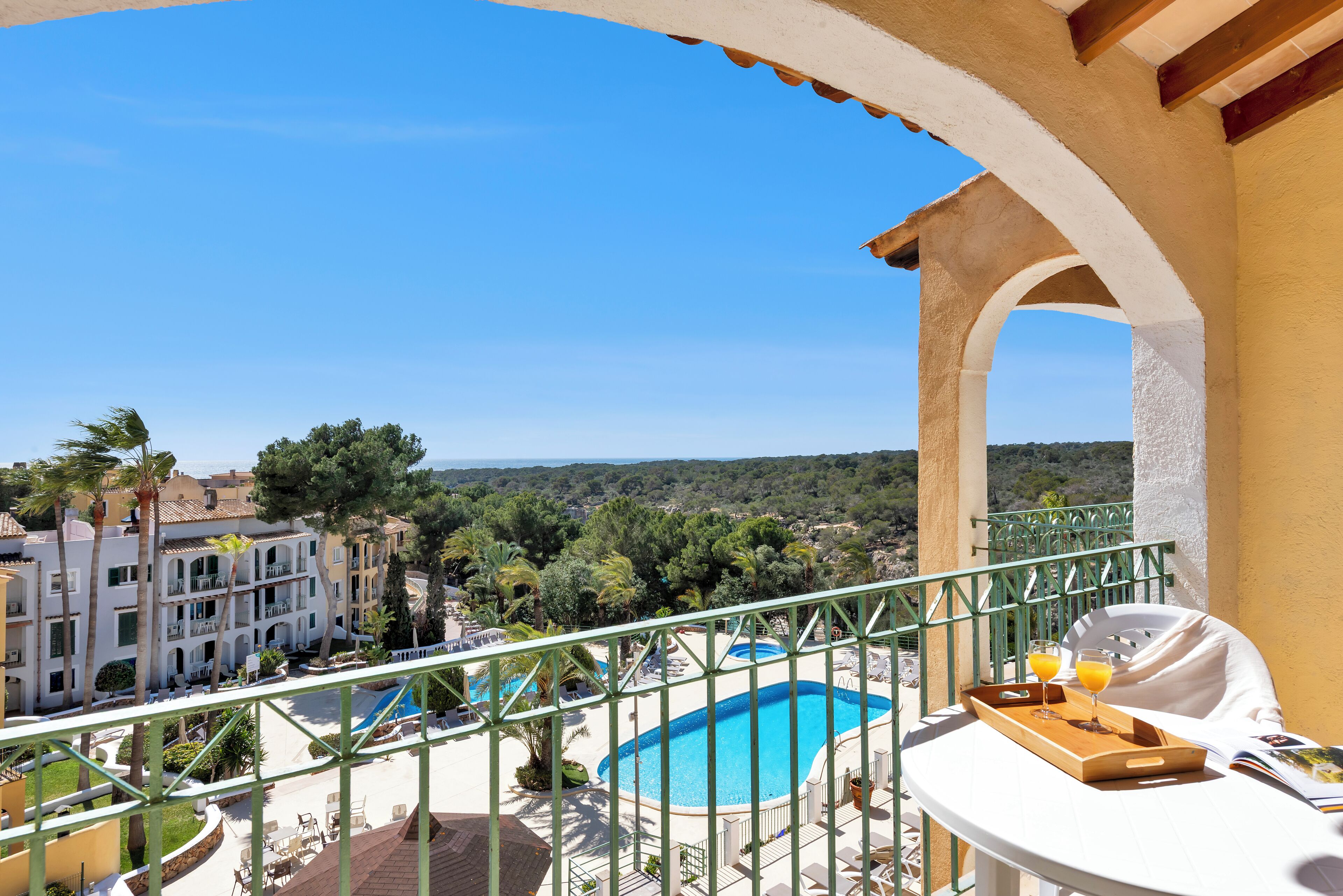 A balcony with a pool view, outdoor seating, and a dining area with a tray.