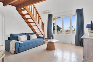 Una sala de estar con un sofá azul, una mesa de centro de madera y una escalera.