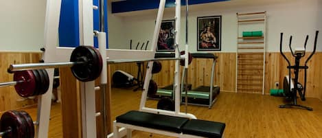 A gym with various exercise equipment, including a bench press, a squat rack, and a treadmill.