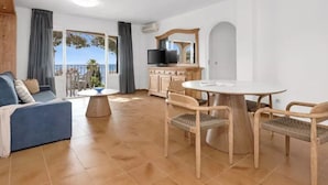 Een woonkamer met een bank, eettafel, stoelen en een televisie.