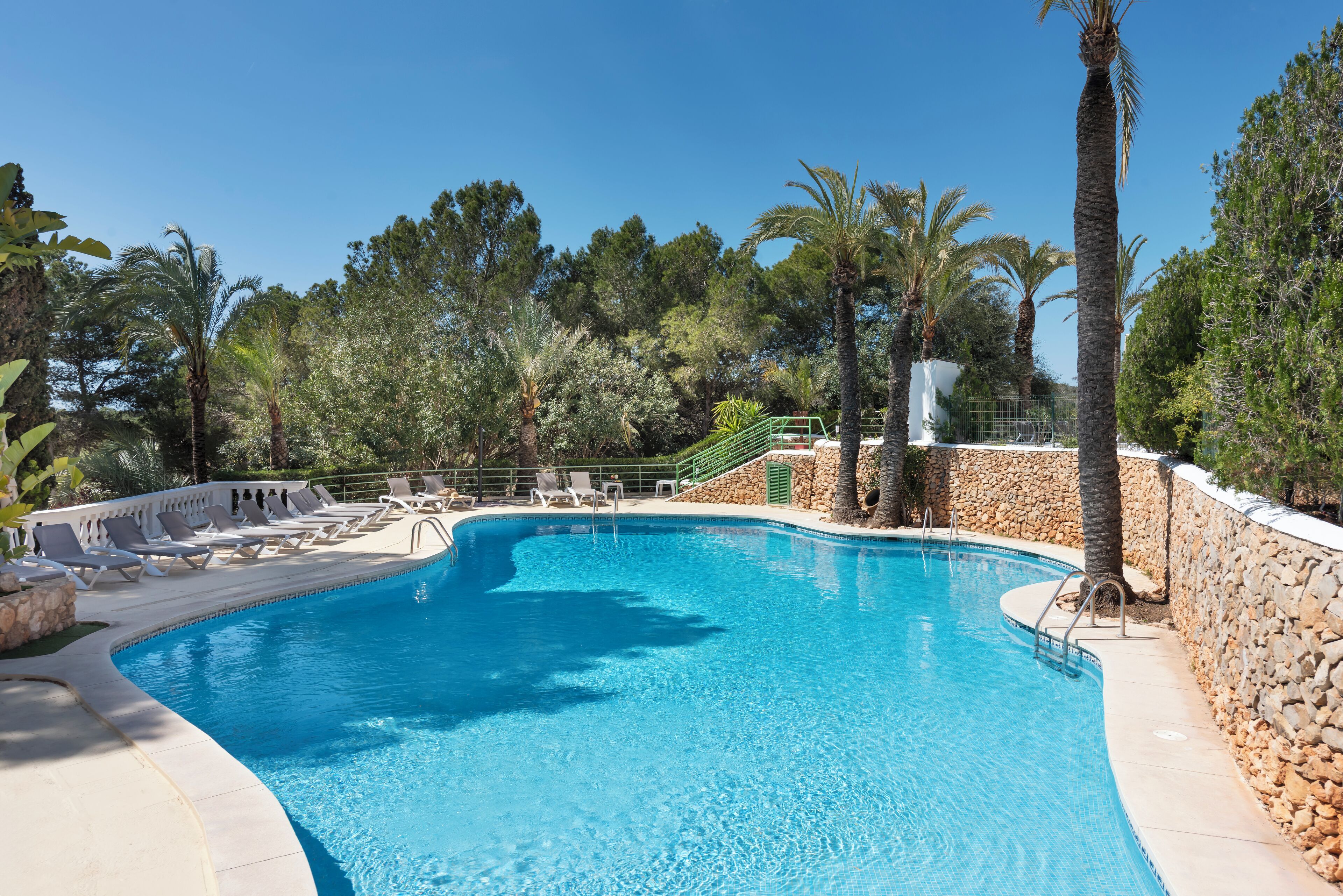 Piscina con sillas de descanso y palmeras.