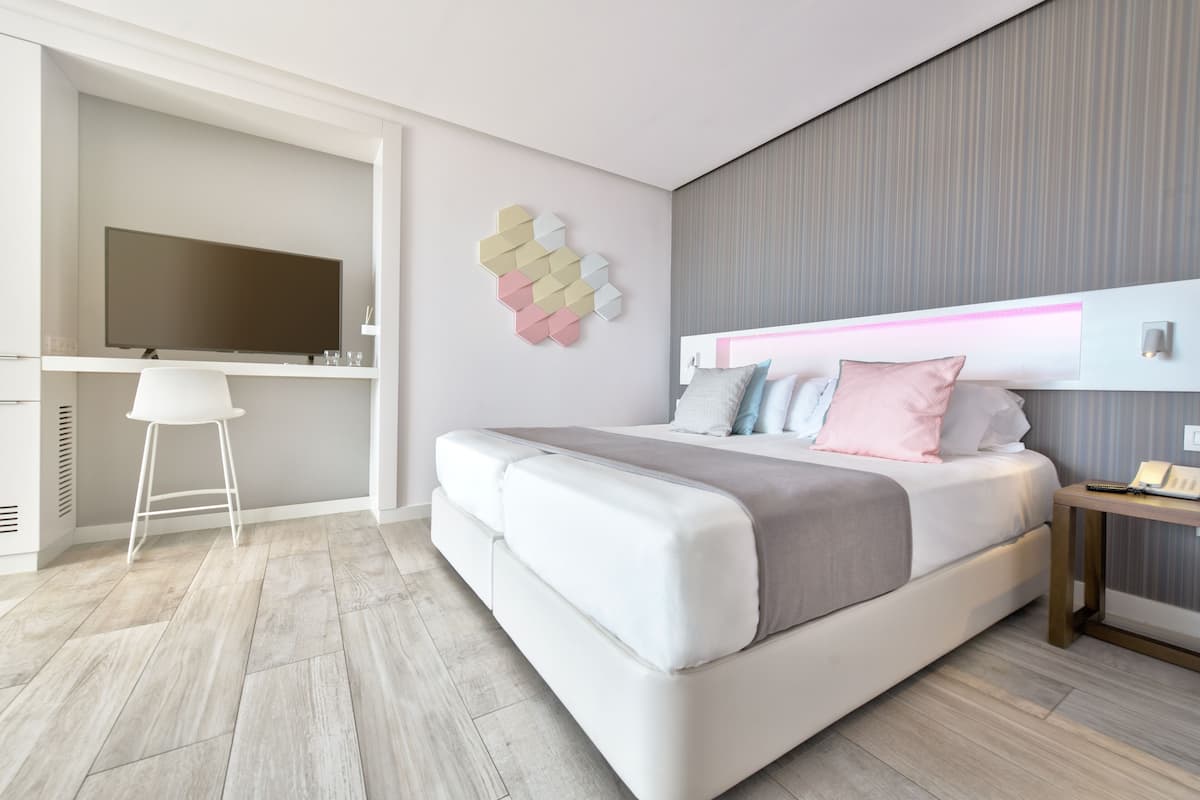 A modern bedroom with a large bed, a TV, and a desk area.