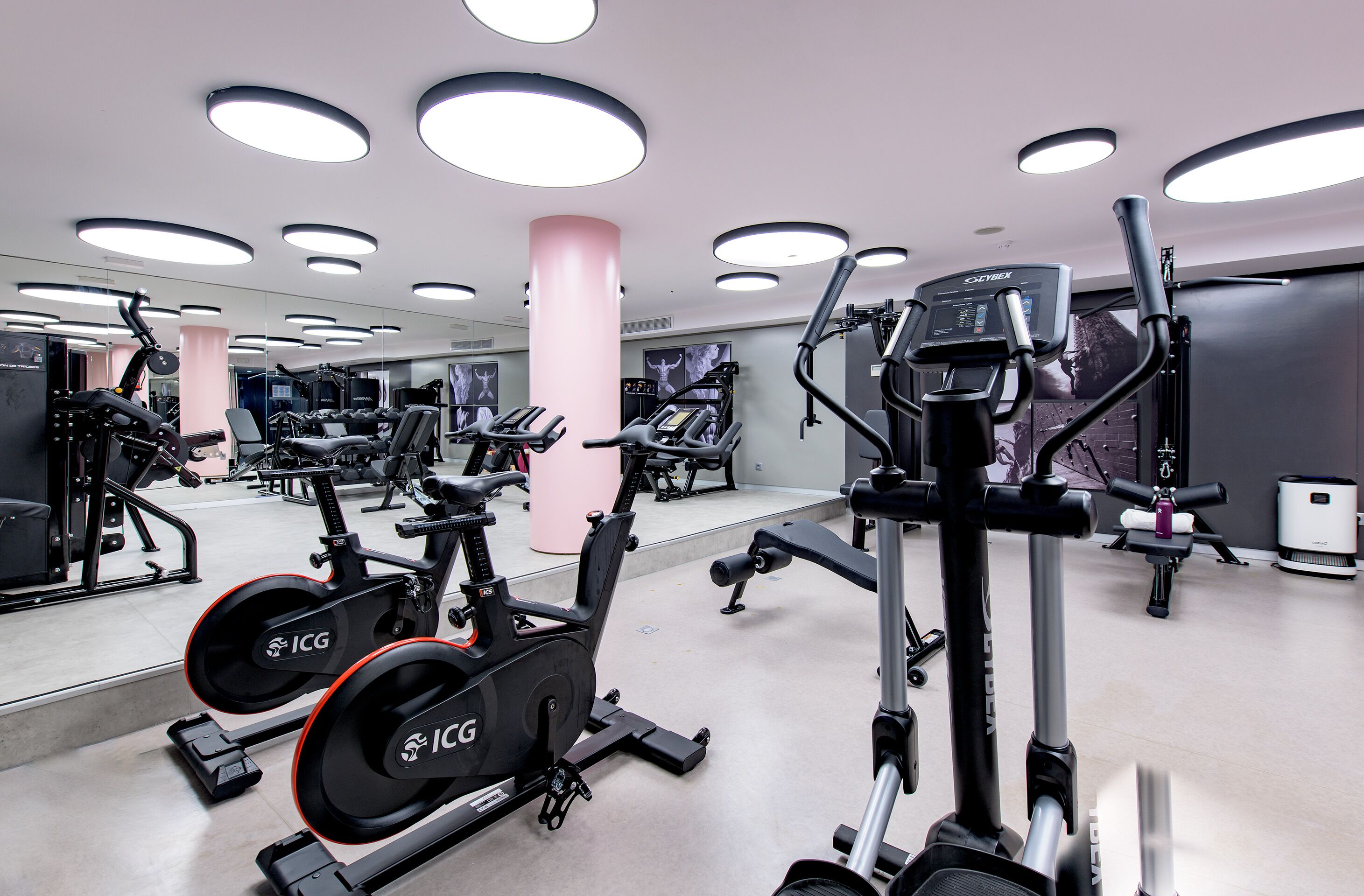 Un gimnasio moderno con diversas máquinas de cardio, espejos y un ambiente limpio y bien iluminado.