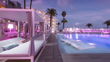 Una piscina techada, una piscina al aire libre, sombrillas
