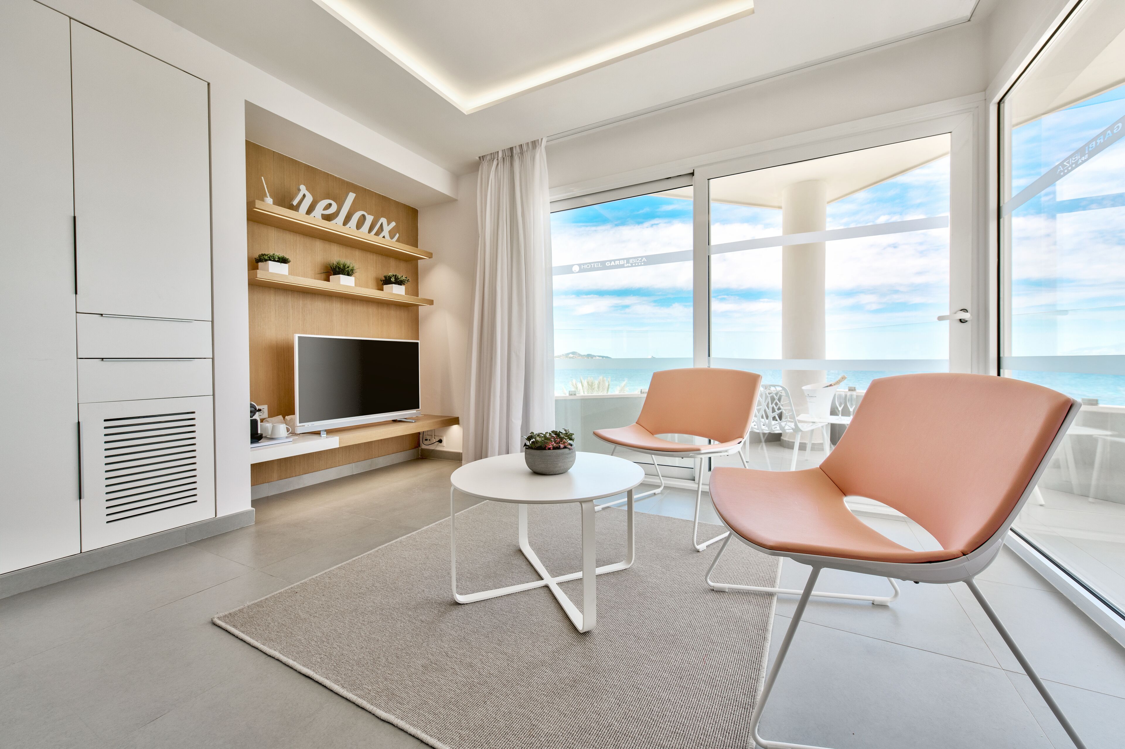 Ein modernes Hotelzimmer mit großem Fenster, Flachbildfernseher, einem kleinen runden Tisch und zwei Stühlen.