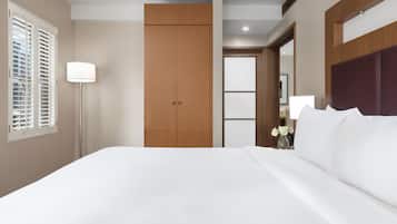 A hotel room with a large bed, a wardrobe, a floor lamp, and a door leading to another room.
