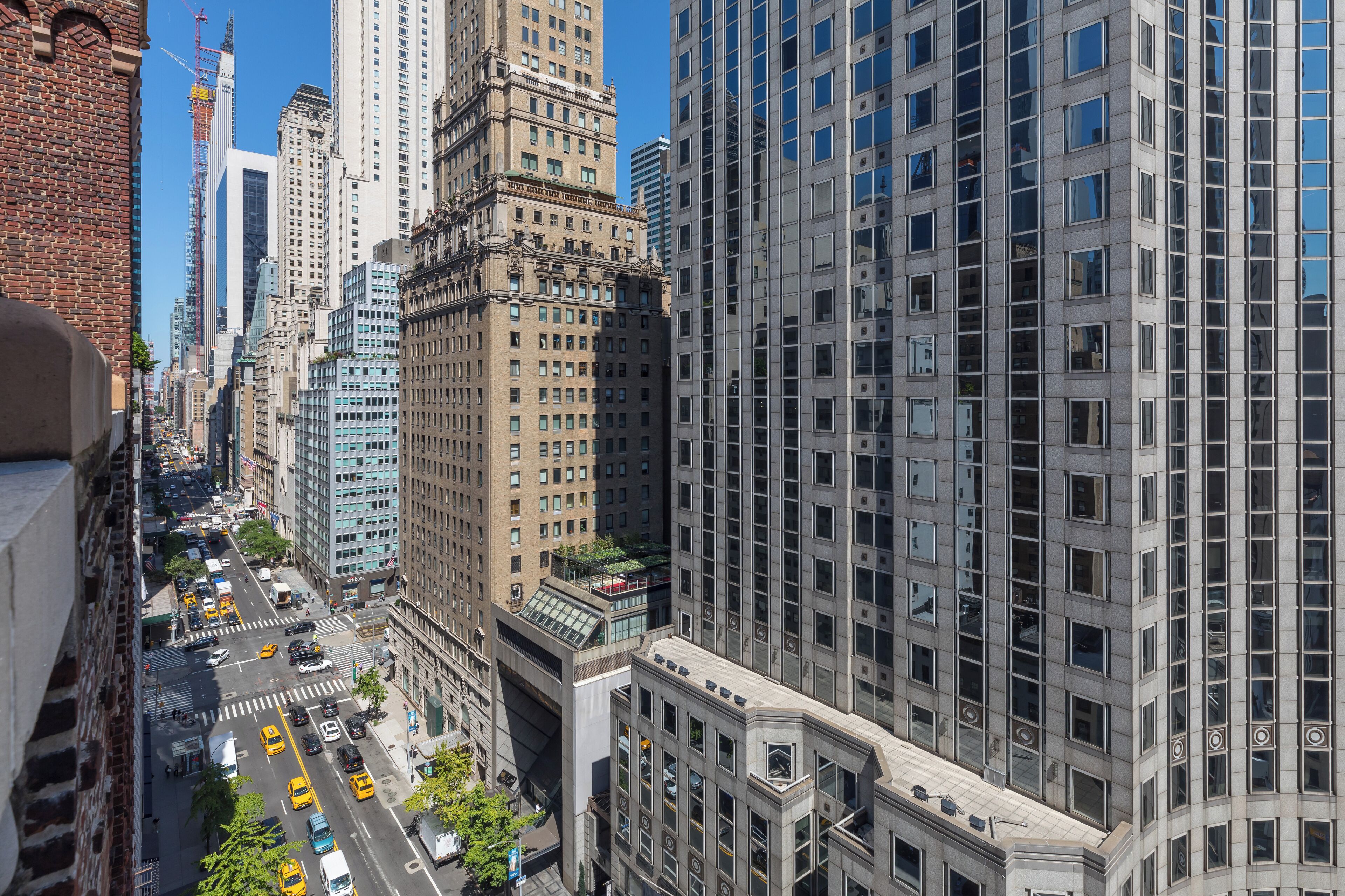 A cityscape with tall buildings, a busy street with vehicles, and a clear blue sky.
