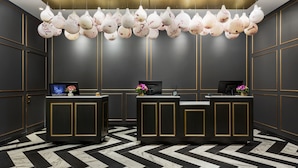 A reception area with two counters, a modern chandelier, and a black and white patterned floor. - Hotel 57 (New York)