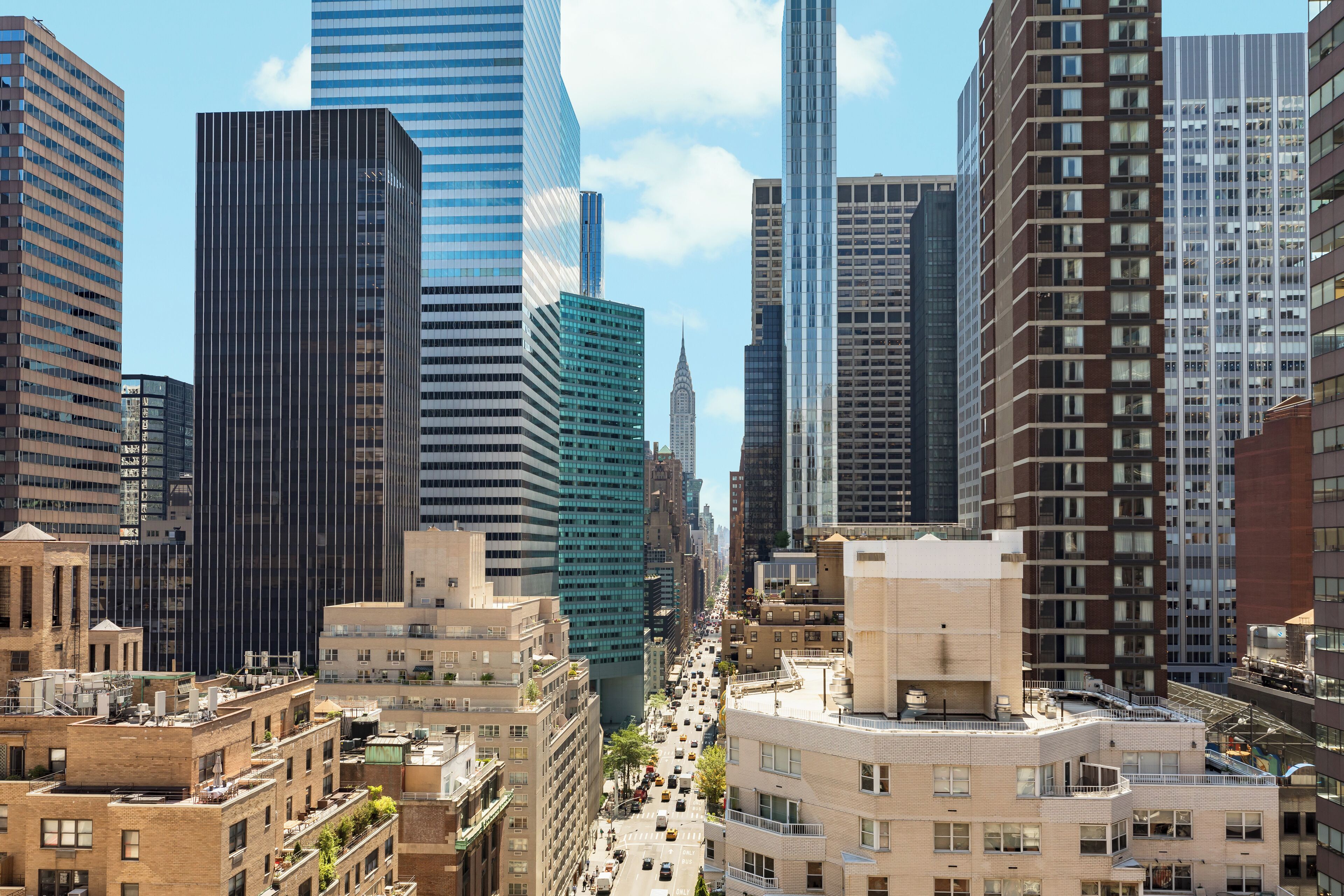 Un paisaje urbano con edificios altos, una calle concurrida y cielo despejado.