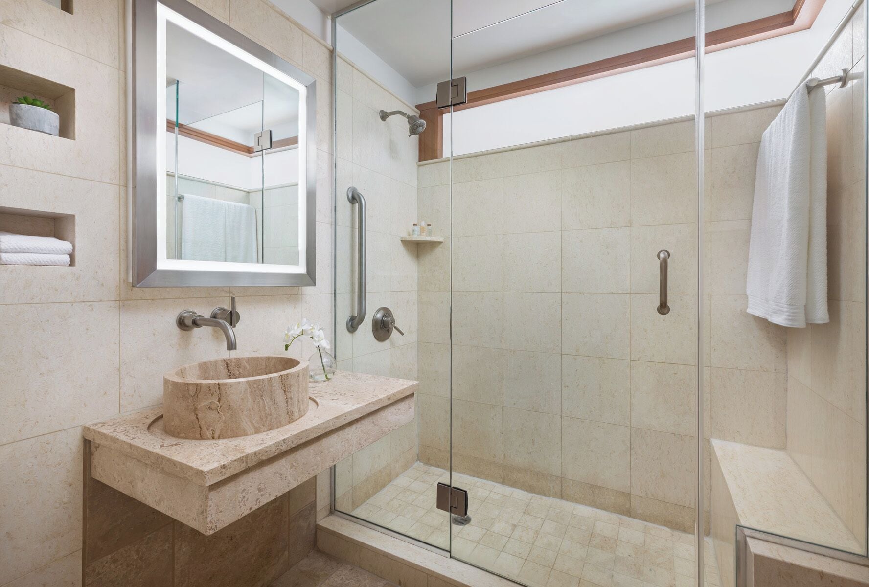 A modern bathroom with a marble sink, glass shower enclosure, and a large mirror.
