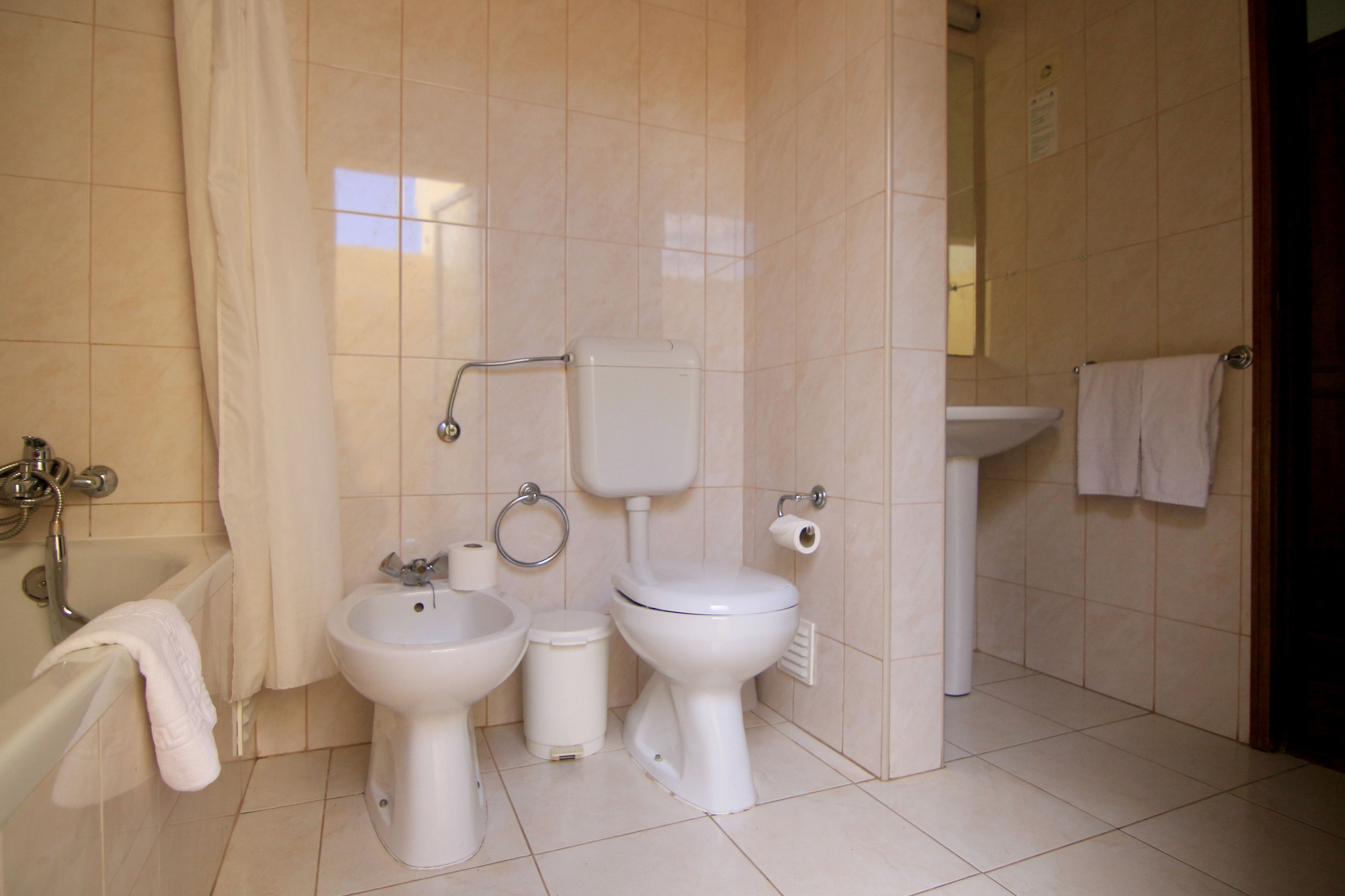 A bathroom with a bathtub, two sinks, a toilet, and a bidet.