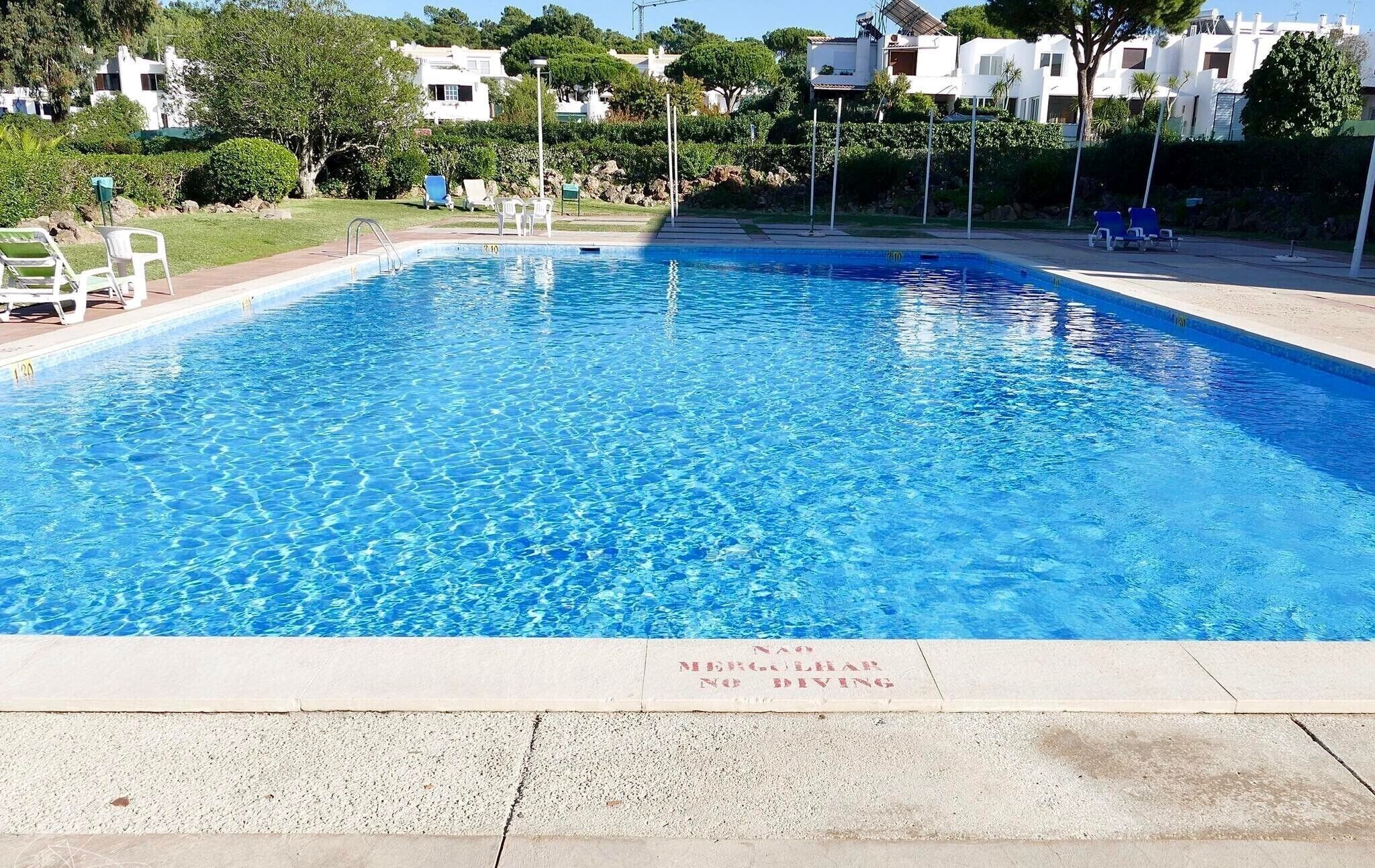 A rectangular swimming pool with clear blue water, surrounded by a concrete deck.