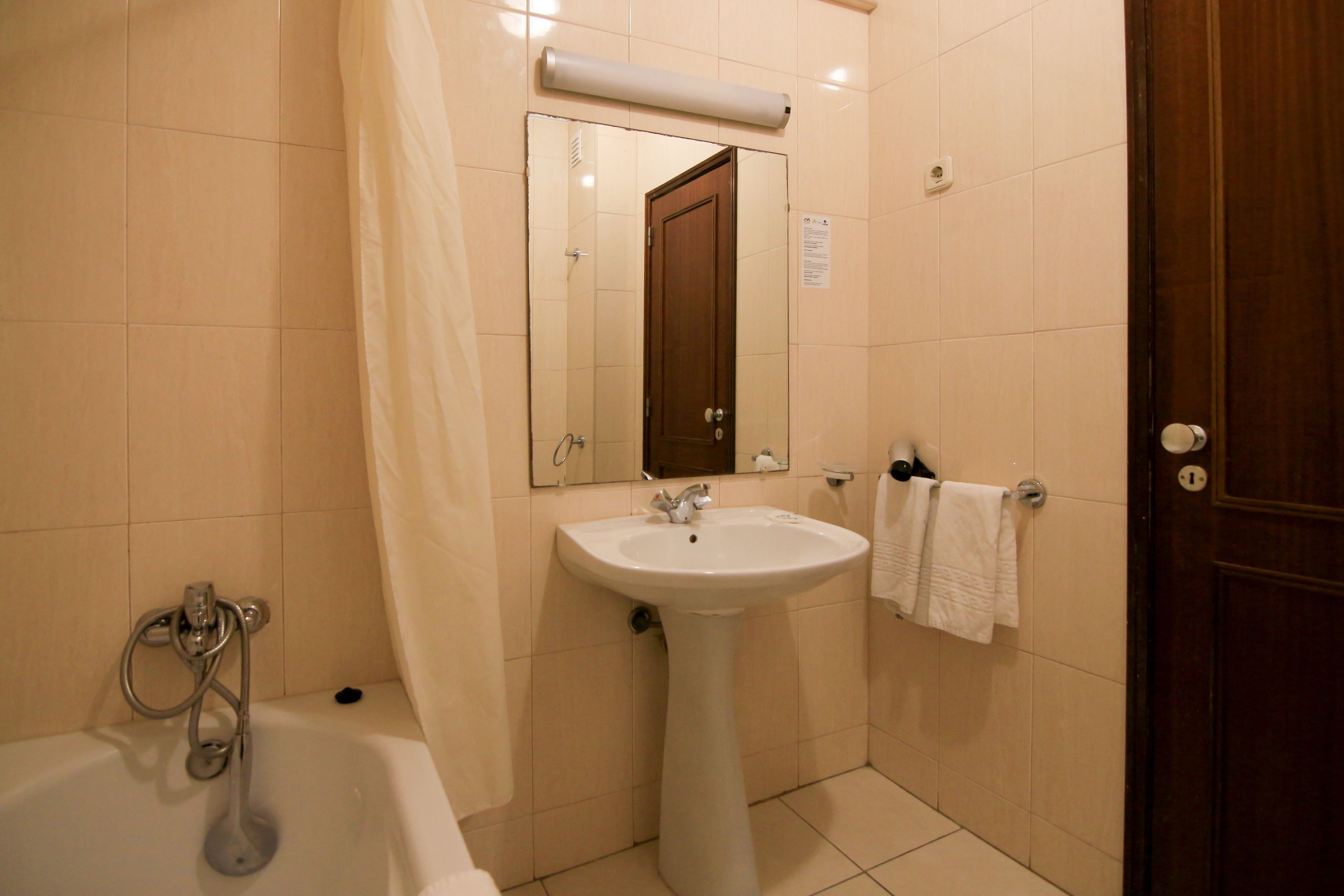 Een badkamer met een bad, een wastafel, een spiegel en een handdoekhouder.