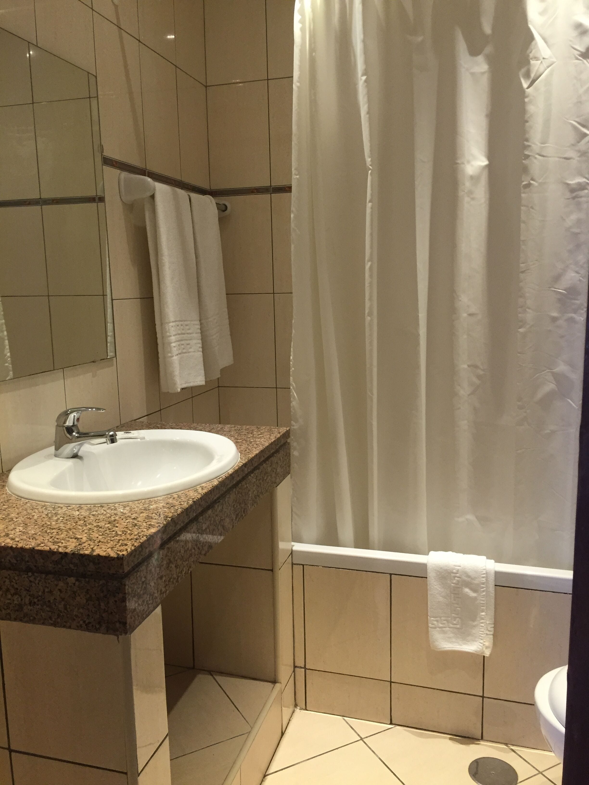 A bathroom with a sink, mirror, and shower curtain.