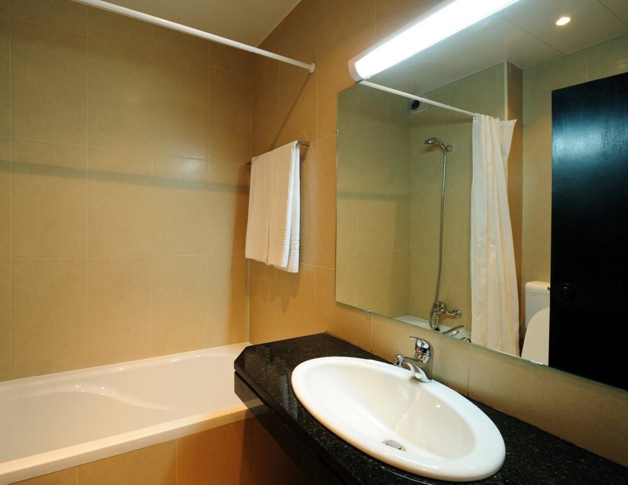 A modern bathroom with a bathtub, a sink, and a large mirror.