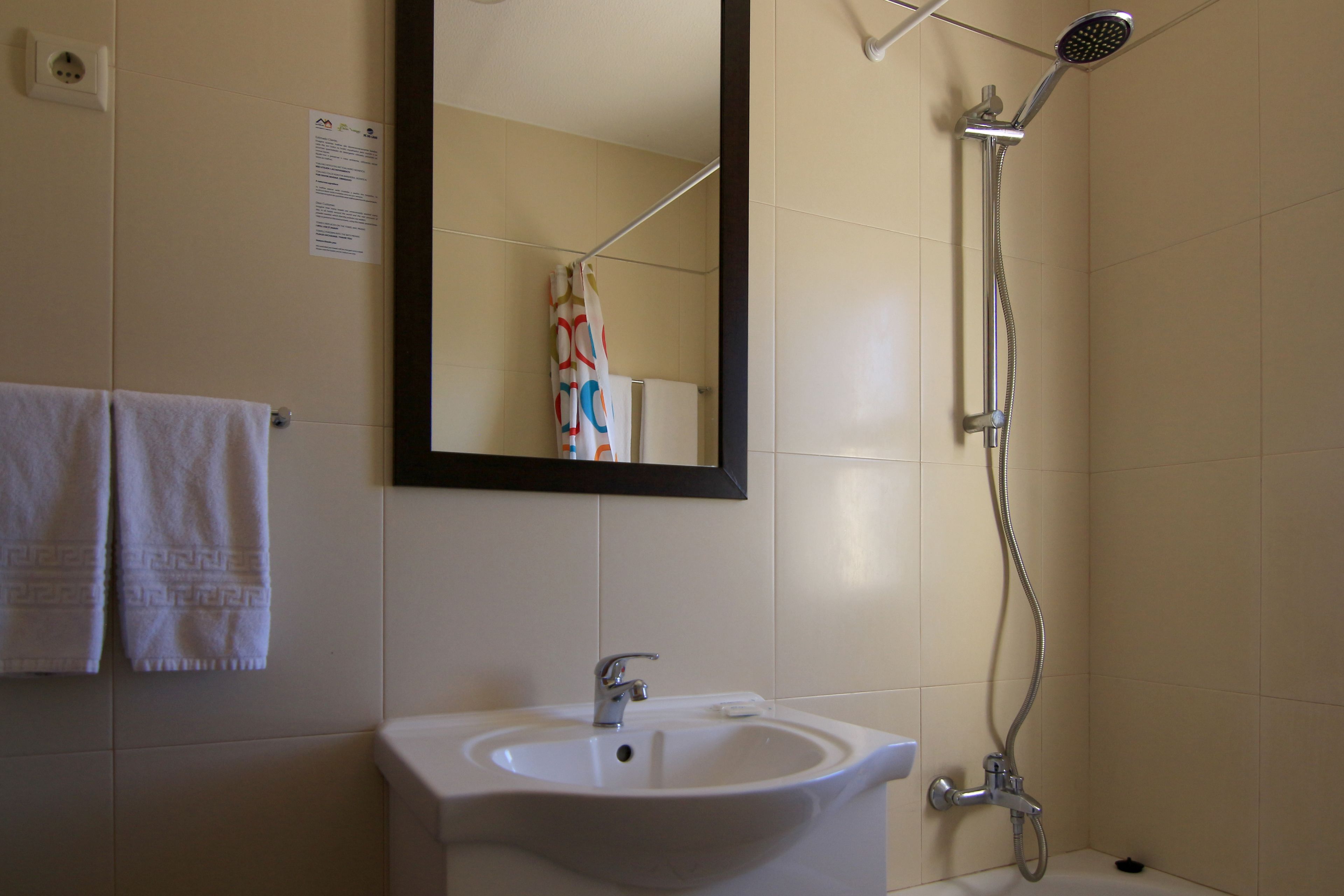 Un baño con lavamanos, espejo y ducha.