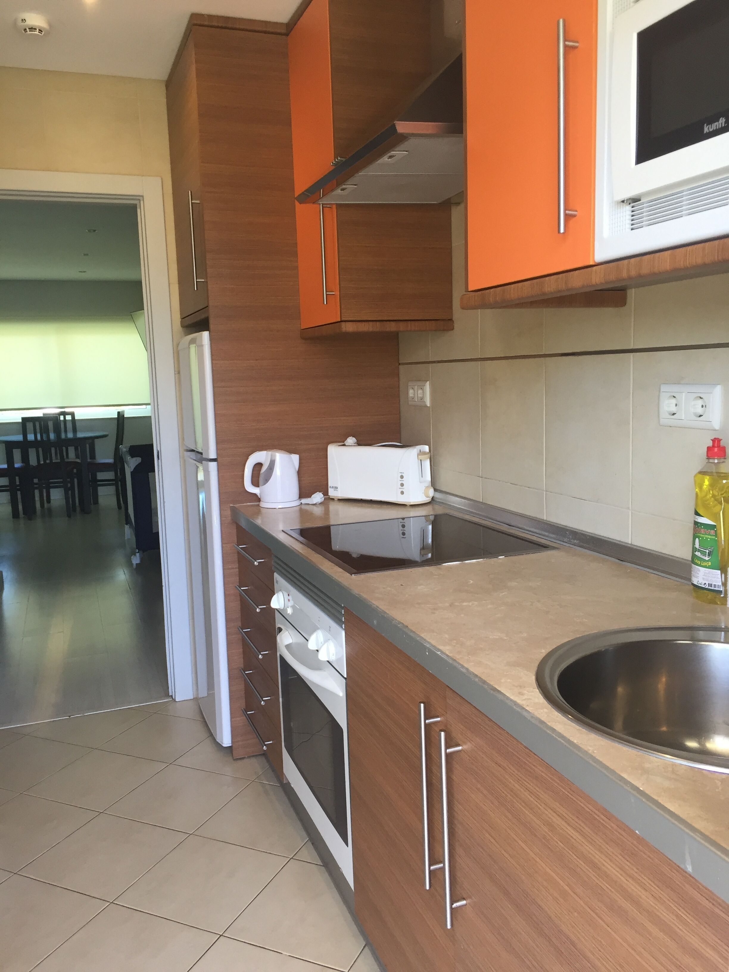 A kitchen with wooden cabinets, a stainless steel sink, a built-in oven, and a microwave.