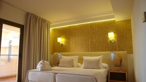 A hotel room with a double bed, two bedside tables with lamps, a small bedside table with a vase, and a sliding glass door to the balcony. - Invisa Hotel La Cala (Santa Eulalia del Rio)