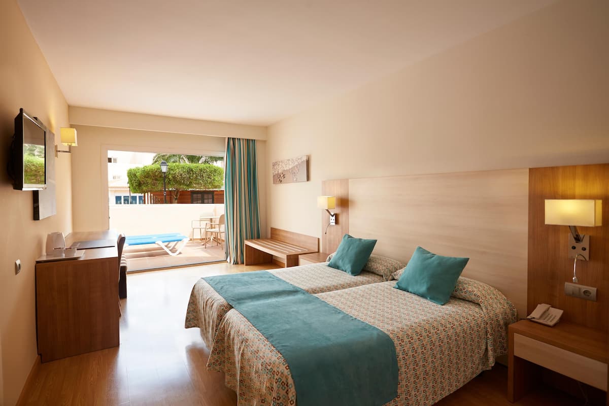 Une chambre d’hôtel avec deux lits, un bureau, une chaise et une petite table.