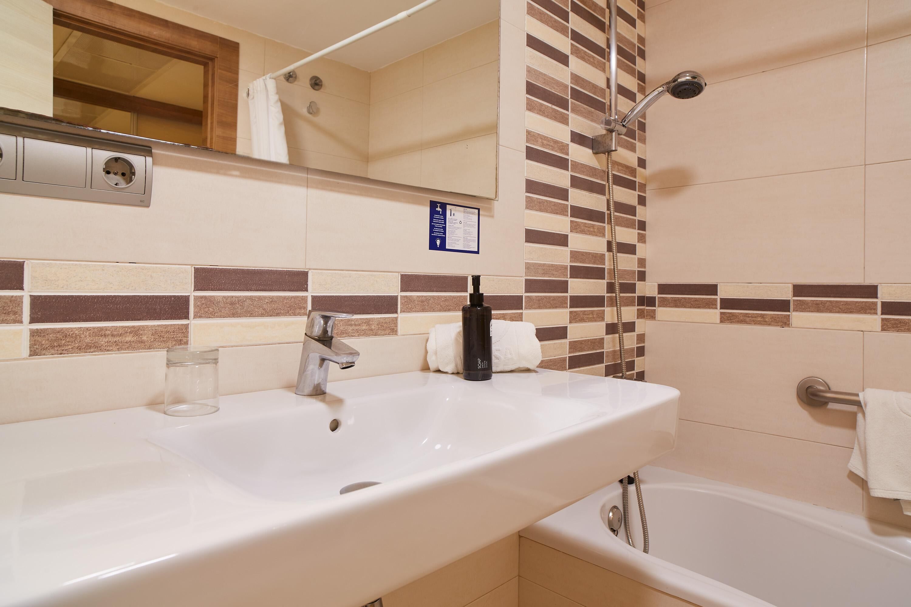Un baño con lavamanos, espejo y ducha.