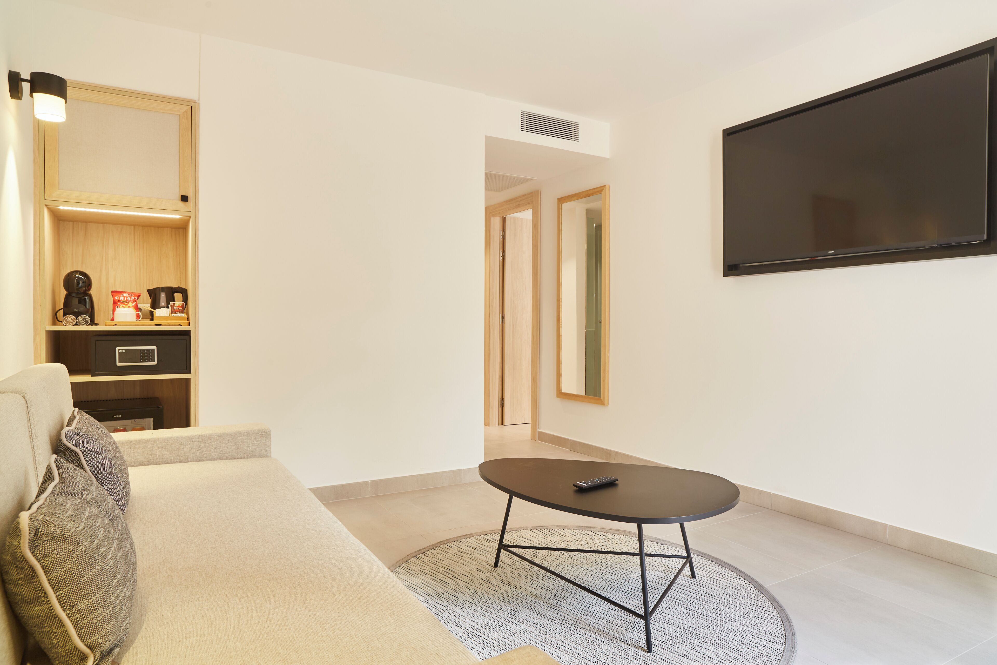 Una sala de estar moderna con un sofá, una mesa de centro y un televisor de pantalla plana montado en la pared.
