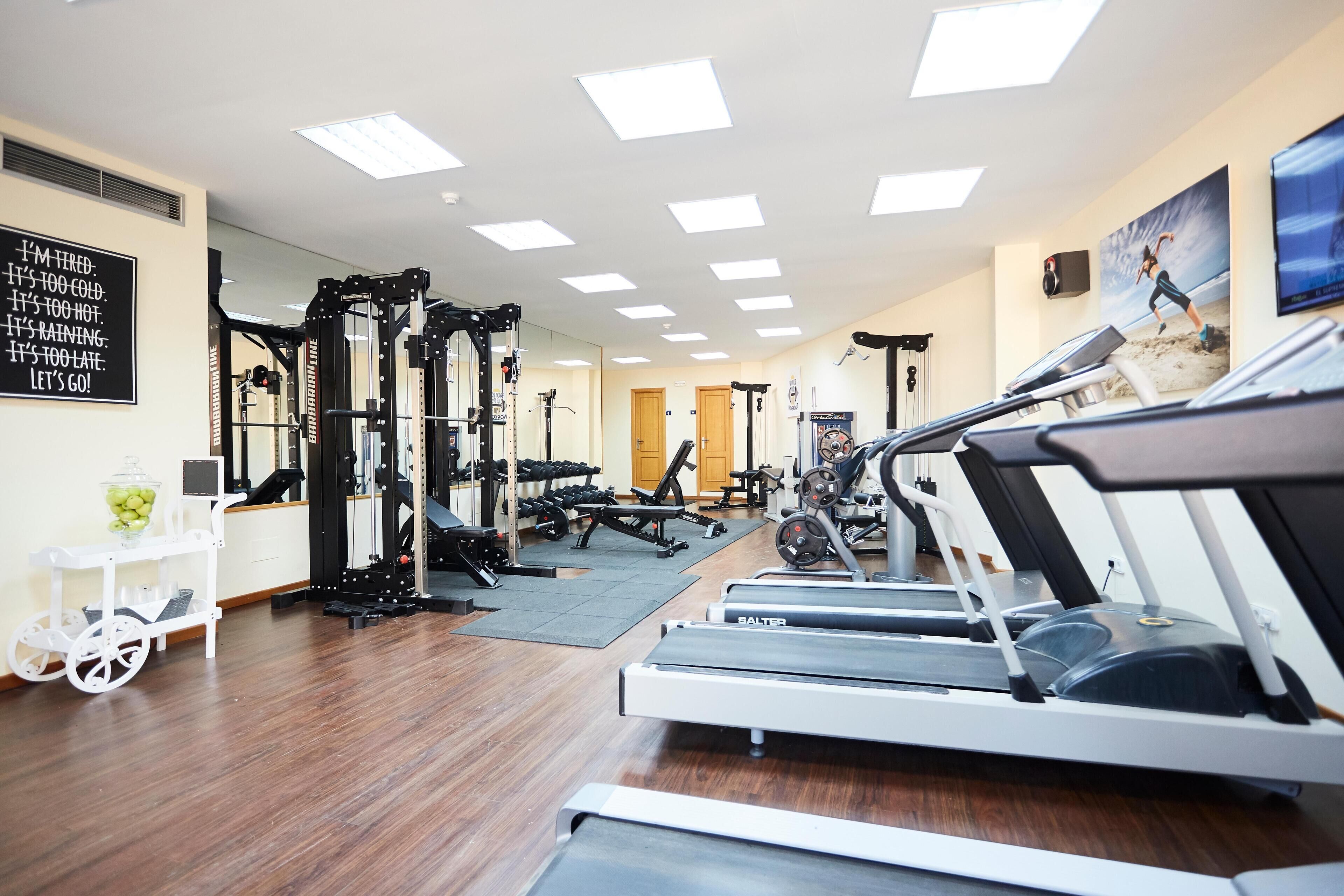 A gym with treadmills, weight machines, and a motivational quote on the wall.