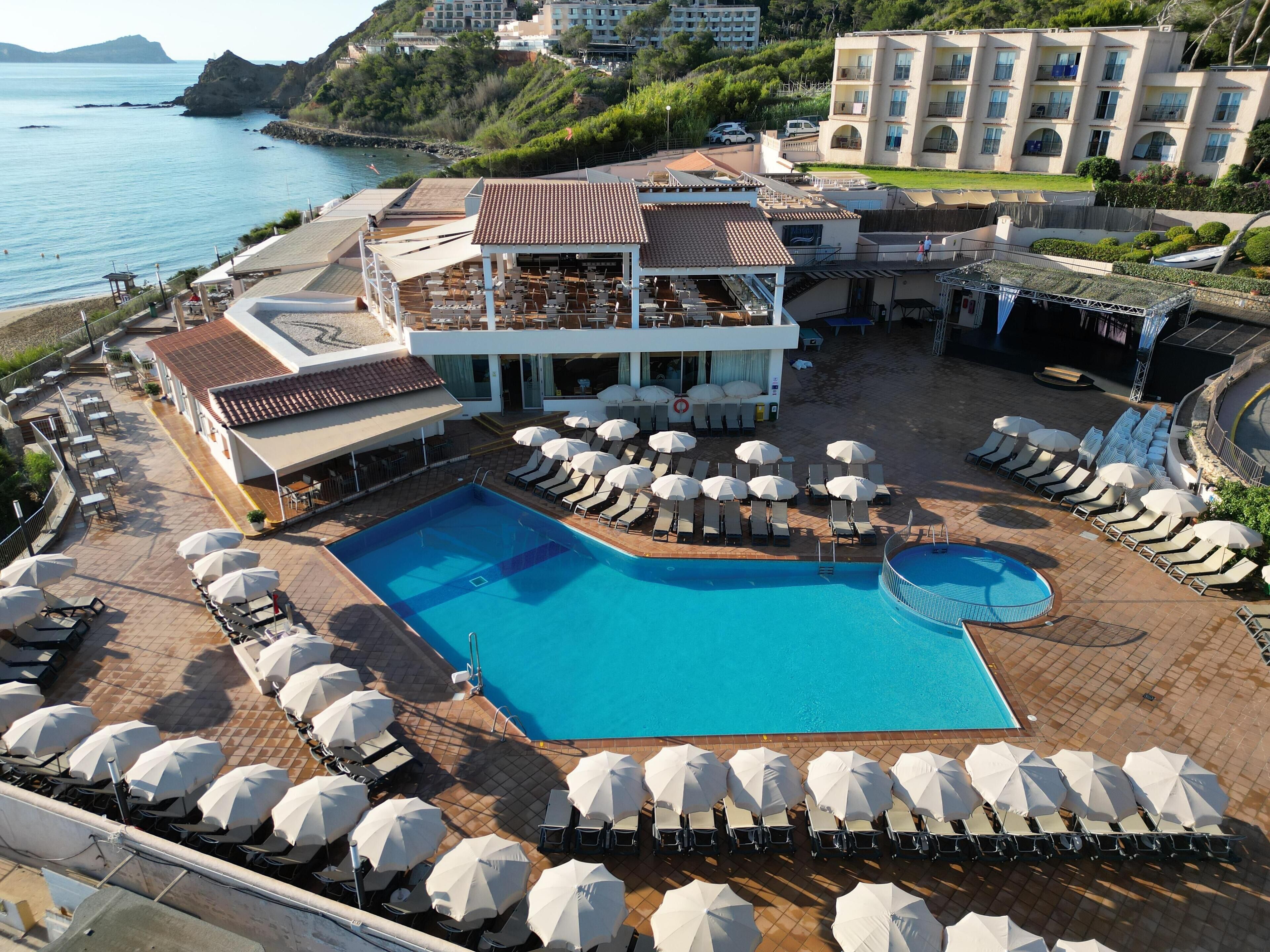 A resort with a large pool, sun loungers, and umbrellas.