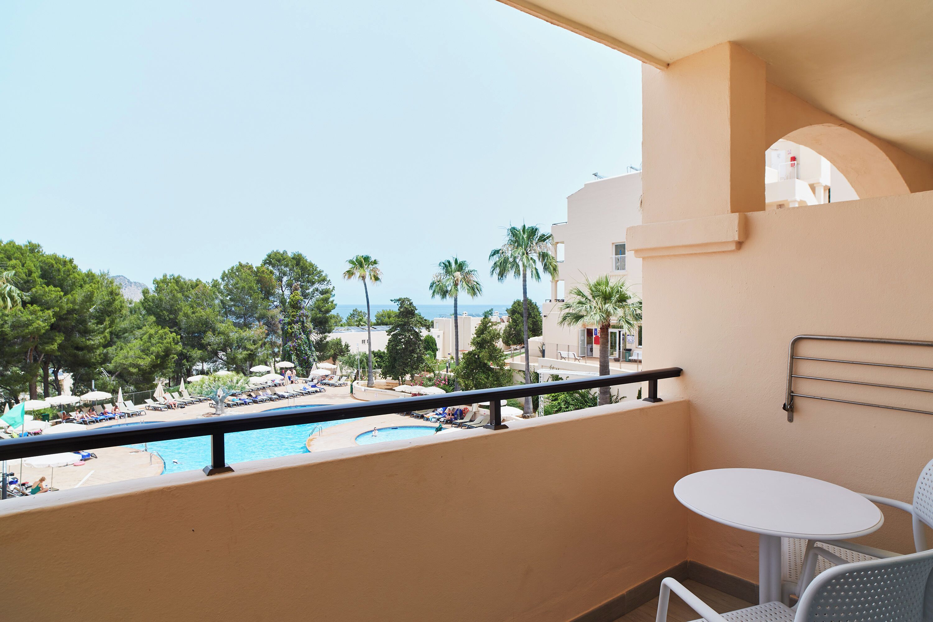 Un balcon donnant sur un espace piscine, comprenant des chaises longues et des parasols.