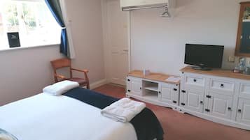 A hotel room with a bed, a chair, a TV, and a wardrobe.