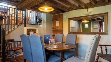 A dining area with a wooden table, blue upholstered chairs, and a mirror on the wall.