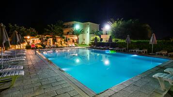 Una piscina al aire libre, sillones reclinables de piscina