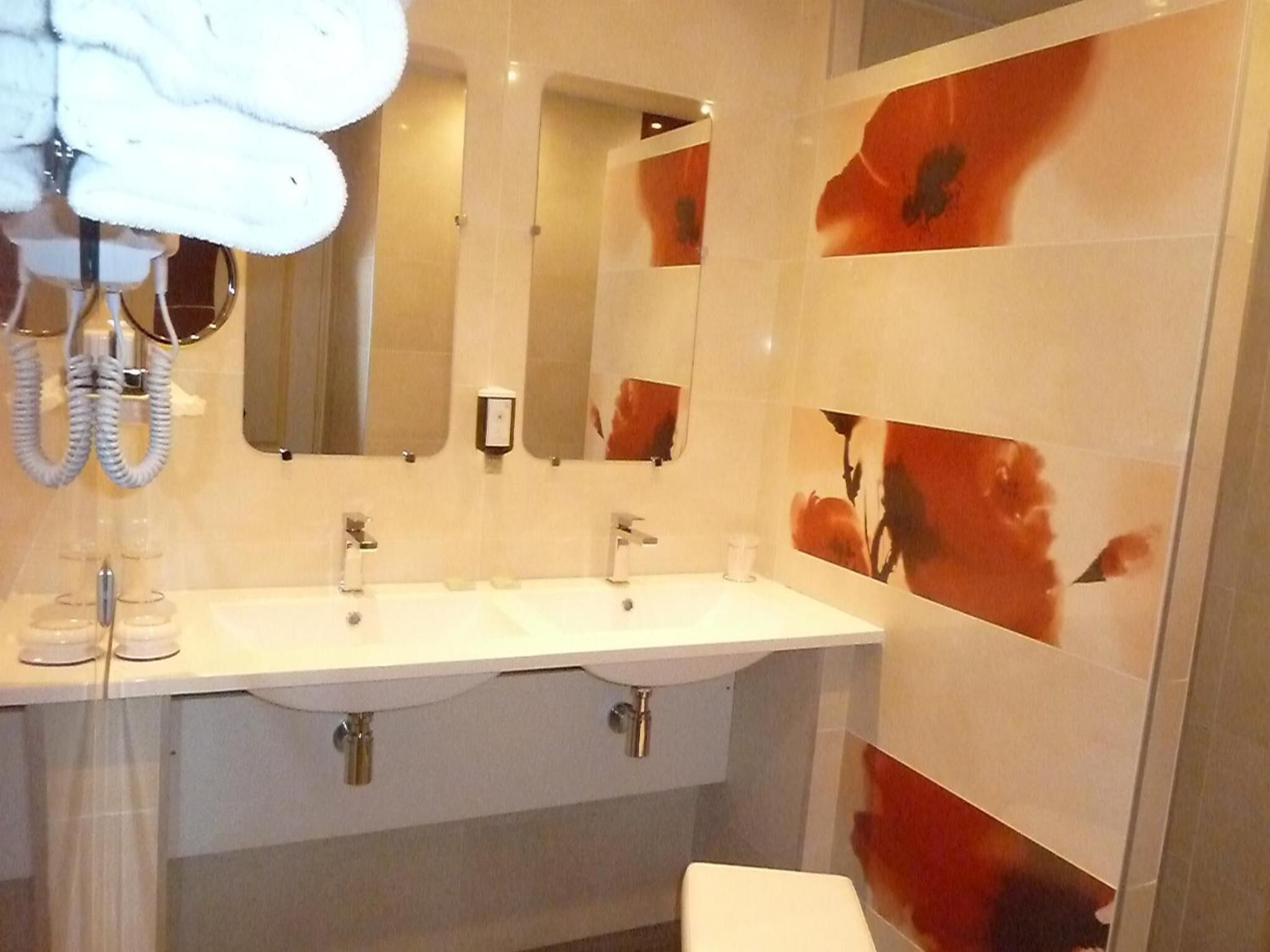 A bathroom with a white sink, two mirrors, and a towel rack.