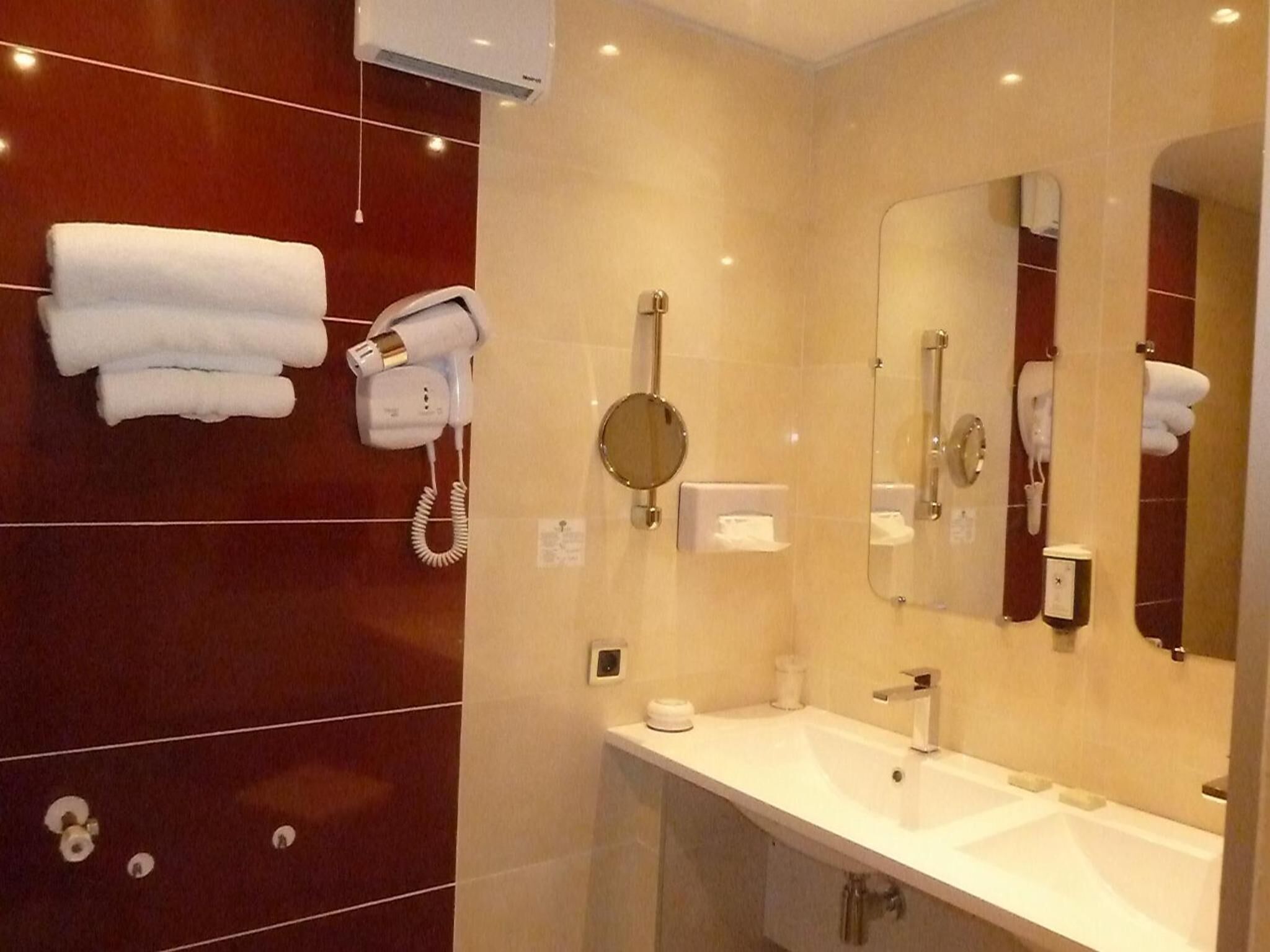 Un baño moderno con tocador, espejo, secador de pelo y toallero.