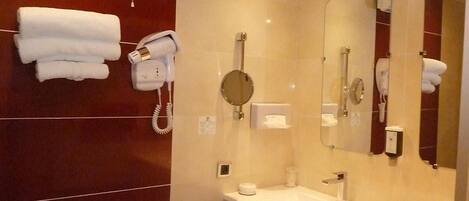 A modern bathroom with a vanity, a mirror, a hairdryer, and a towel rack.
