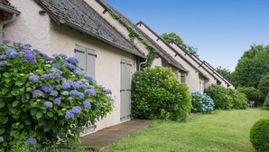 A row of traditional houses with a well-maintained garden and a wooden pathway. - The Originals Relais, Hôtel Restaurant Les Coquelicots (Saint-Pardoux-l'Ortigier)
