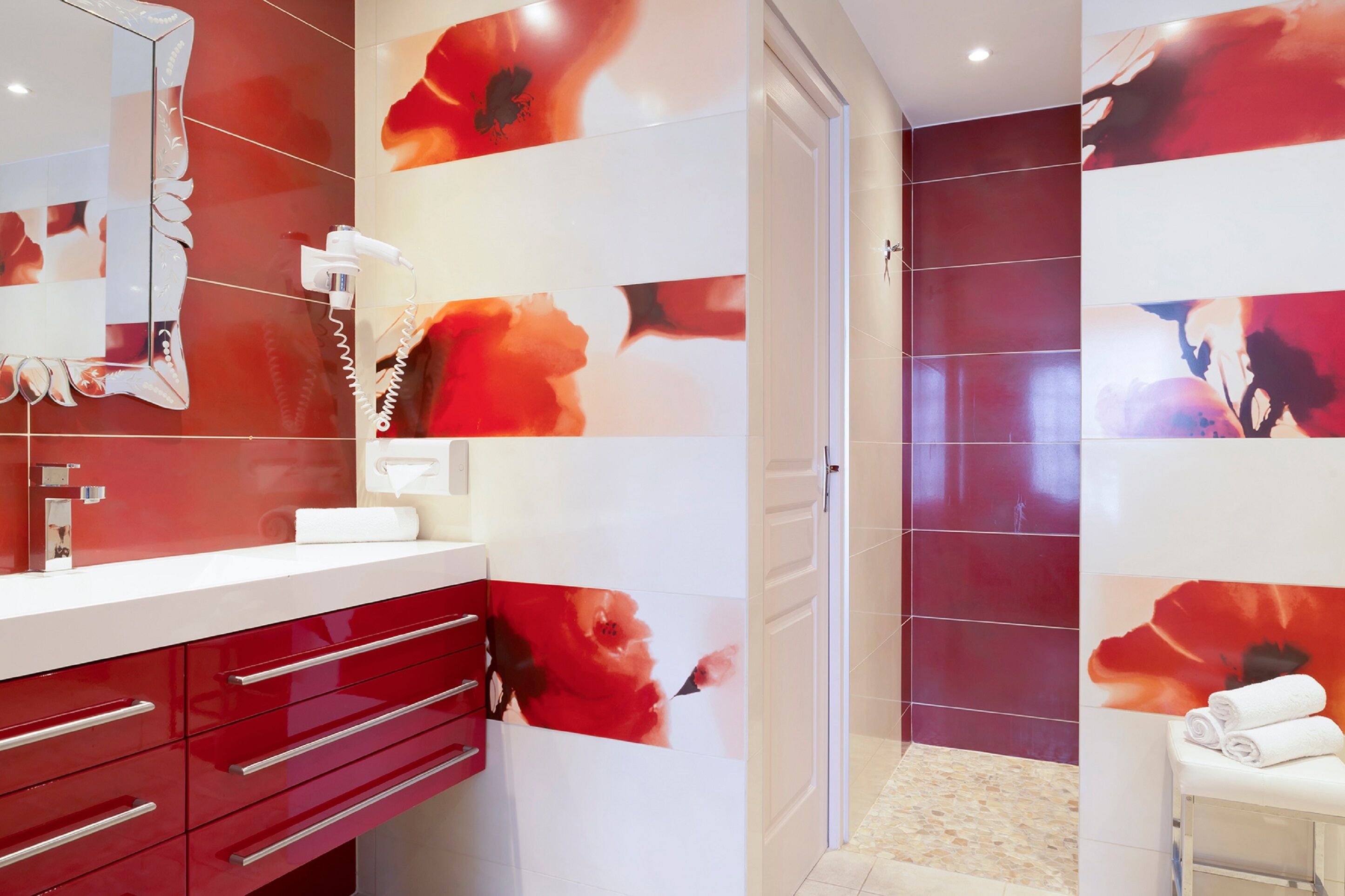 Une salle de bain moderne aux couleurs rouge et blanc, dotée d’un grand miroir et d’un porte-serviettes.