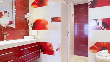 Une salle de bain moderne aux couleurs rouge et blanc, dotée d’un grand miroir et d’un porte-serviettes.