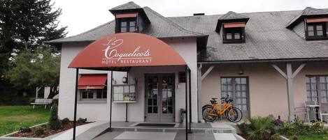 A hotel with a red awning and a bicycle parked outside.