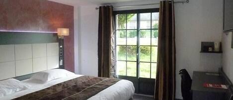 Habitación de hotel con una cama grande, un escritorio y una ventana con cortinas.