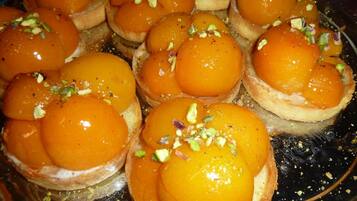 A tray of pastries topped with orange custard and garnished with chopped nuts.
