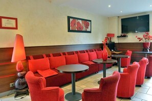 A modern lounge area with red seating, a fireplace, and a television. - The Originals Relais, Hôtel Restaurant Les Coquelicots (Saint-Pardoux-l'Ortigier)