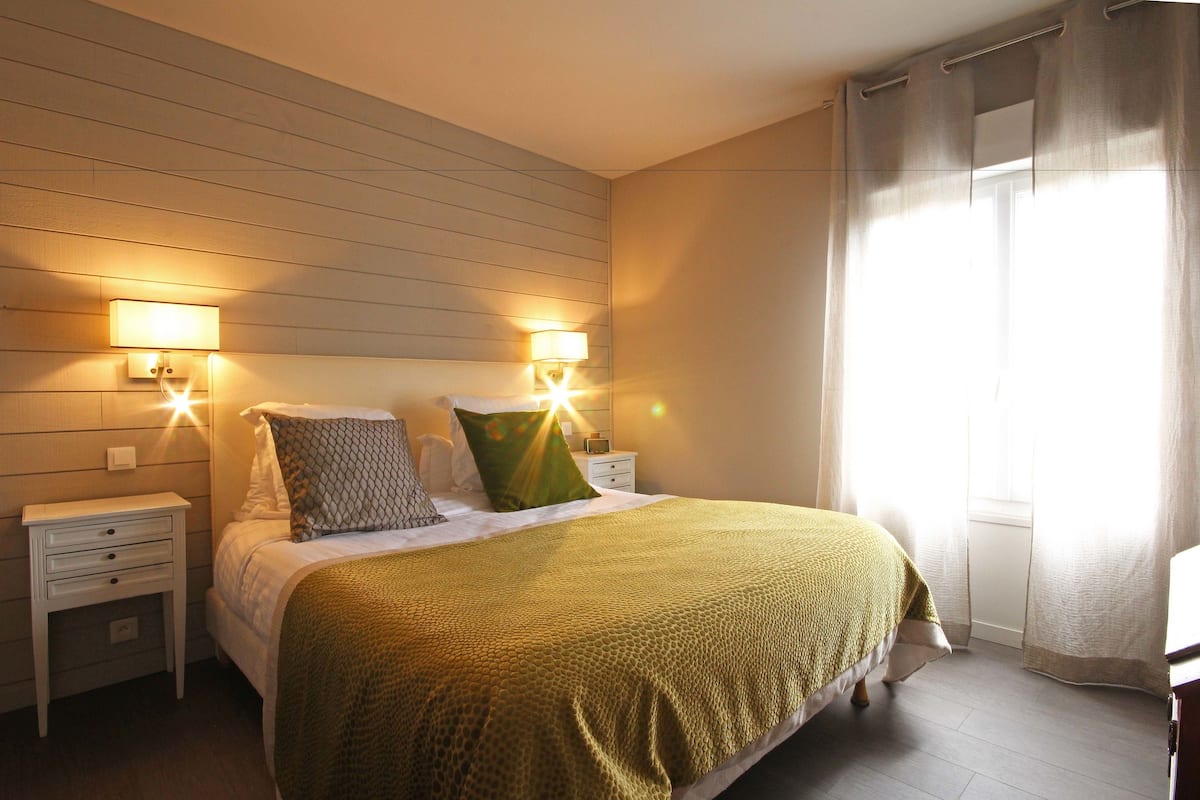 Une chambre à coucher avec un lit, deux tables de chevet et deux lampes fixées au mur.